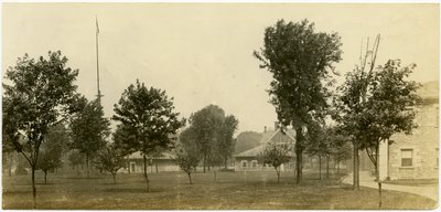 Group of Brick Buildings Bordering on an Open Green Space with Trees Scattered Throughout by Carl Michel
